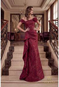 Woman in a merlot color evening gown standing on a staircase in an elegant interior setting.