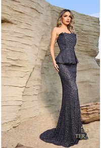 Woman in a strapless, sparkly evening gown standing against a rocky background