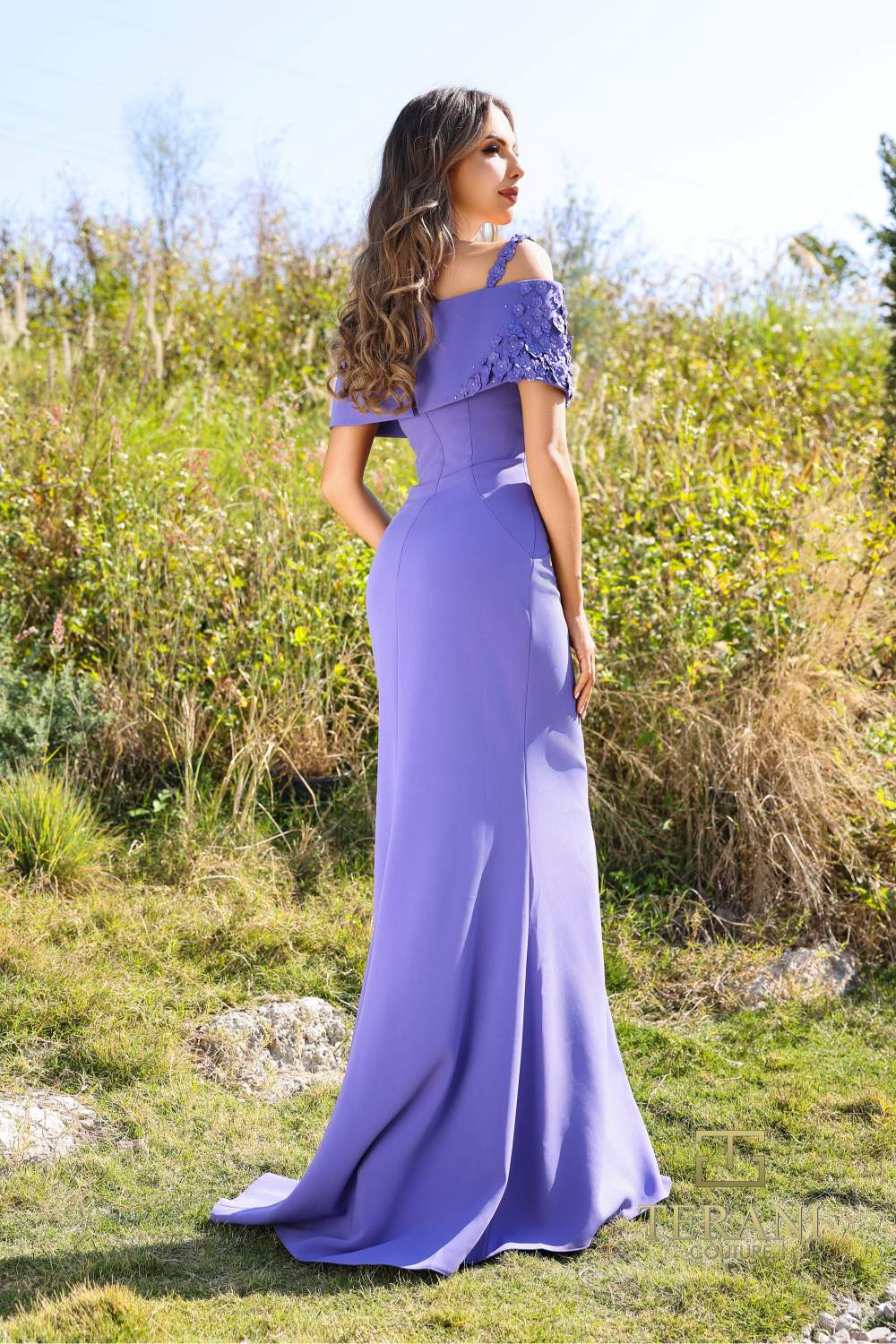 Model wearing Terani Couture 252M5347 cold shoulder evening gown with draped sleeves and fitted silhouette.