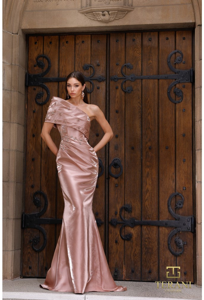 Woman in a pink evening gown standing in front of a large wooden door with metal handles.