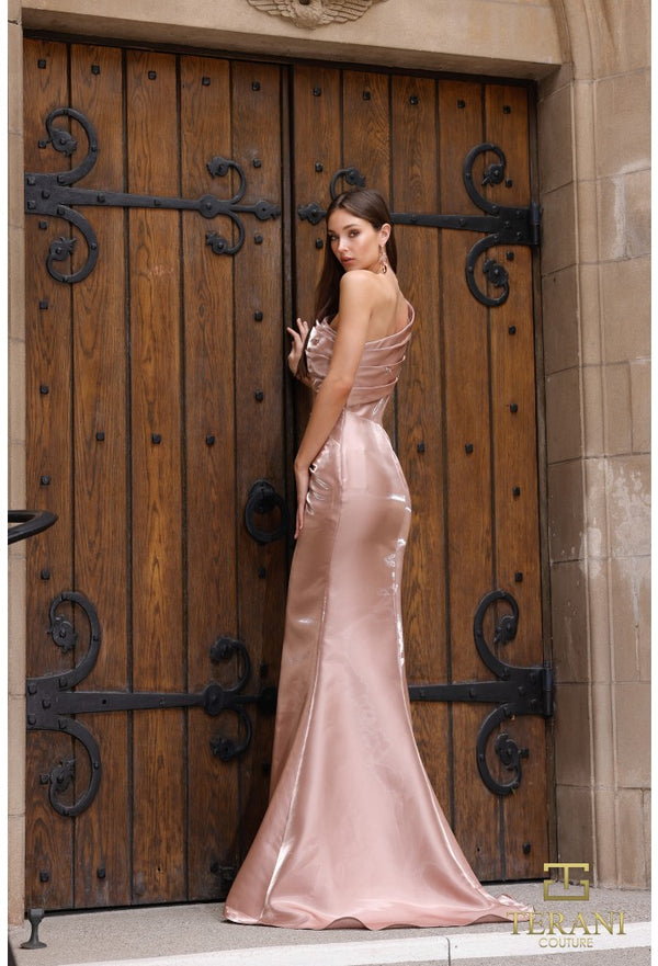 Woman in a pink evening gown standing in front of a large wooden door with intricate black metalwork.