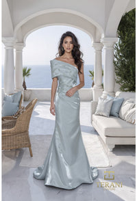 Woman in a sage color off-shoulder gown standing in an outdoor setting with ocean view.