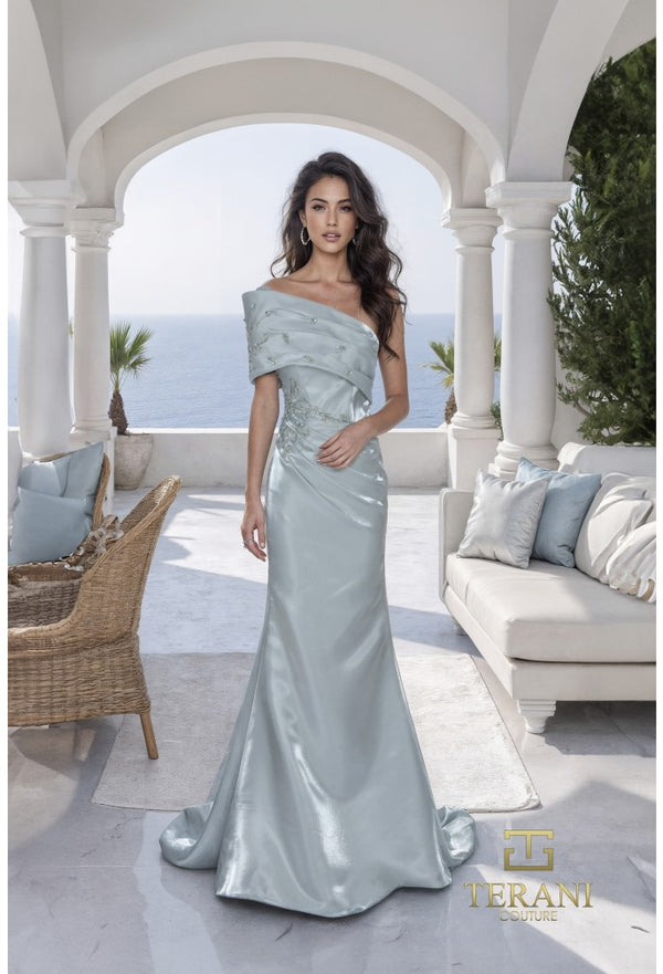 Woman in a sage color off-shoulder gown standing in an outdoor setting with ocean view.