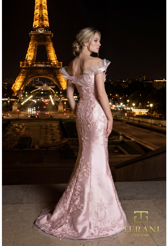 Model wearing the Terani Couture 261E6270 off-the-shoulder fitted gown with floral embellishments and a sweep train.