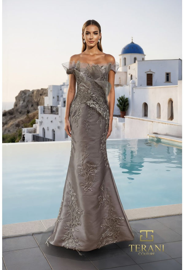 Model wearing the Terani Couture 261E6270 off-the-shoulder fitted gown with floral embellishments and a sweep train.