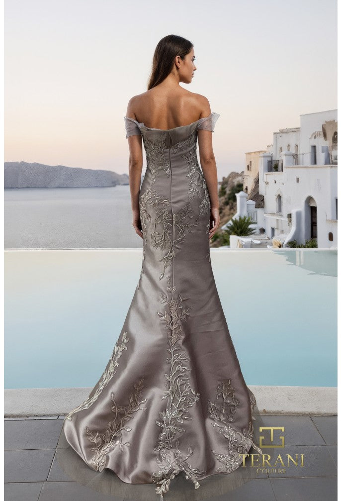 Model wearing the Terani Couture 261E6270 off-the-shoulder fitted gown with floral embellishments and a sweep train.