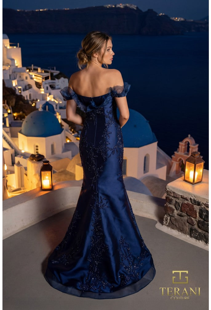 Model wearing the Terani Couture 261E6270 off-the-shoulder fitted gown with floral embellishments and a sweep train.