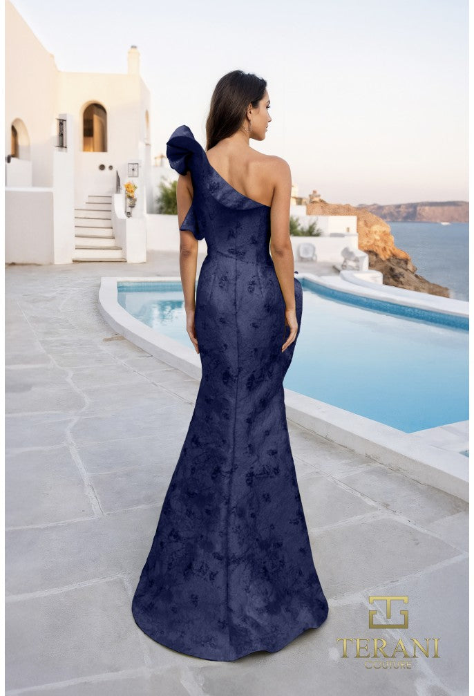Woman in a navy blue one-shoulder gown standing by a pool with a scenic background