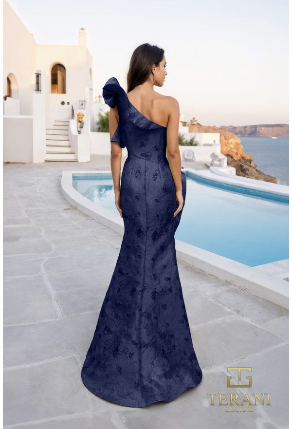 Woman in a navy blue one-shoulder gown standing by a pool with a scenic background
