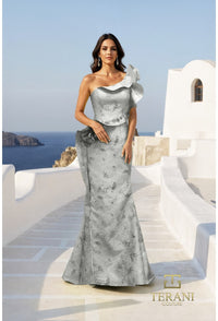 Woman in a silver evening gown standing on a Mediterranean-style patio with ocean view.