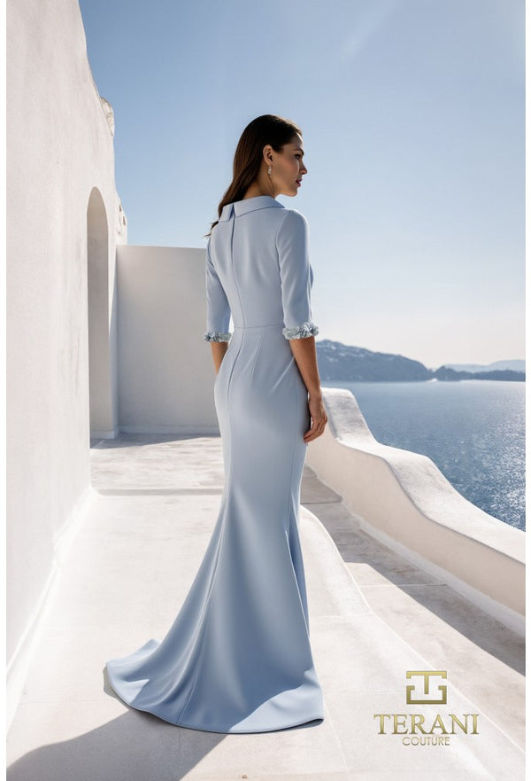 Woman in a light blue dress standing on a balcony with a scenic view of the ocean.