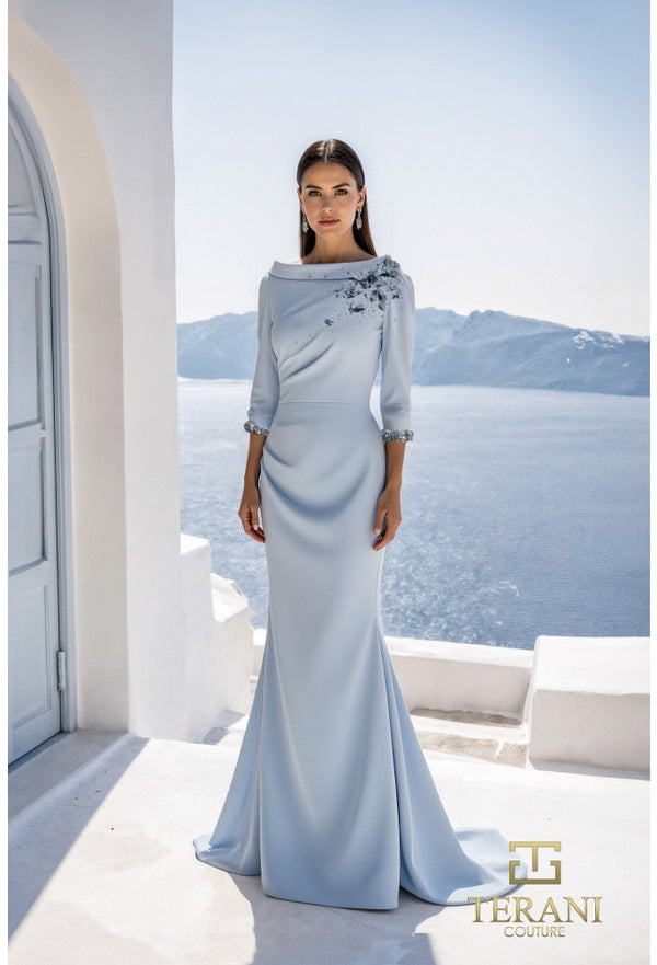 Woman in a light blue evening gown standing in front of a scenic view with 'Terani' branding.