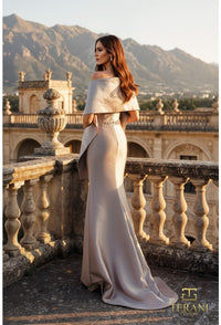 Woman in a elegant off-shoulder gown standing on a balcony with mountains in the background