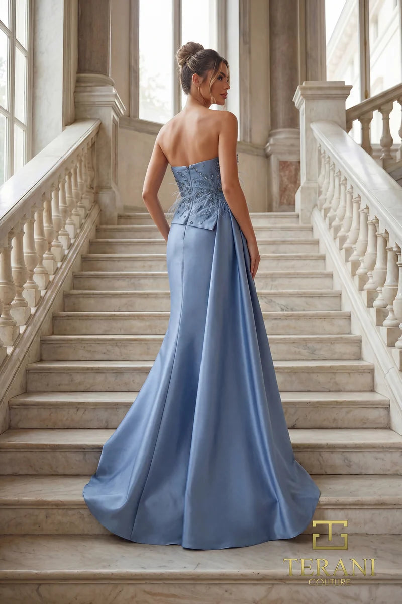 Model wearing Terani Couture 262E7052 one-shoulder evening gown with an embellished bodice, feather-inspired detailing, fitted skirt, and overskirt.  Back View of the dress.