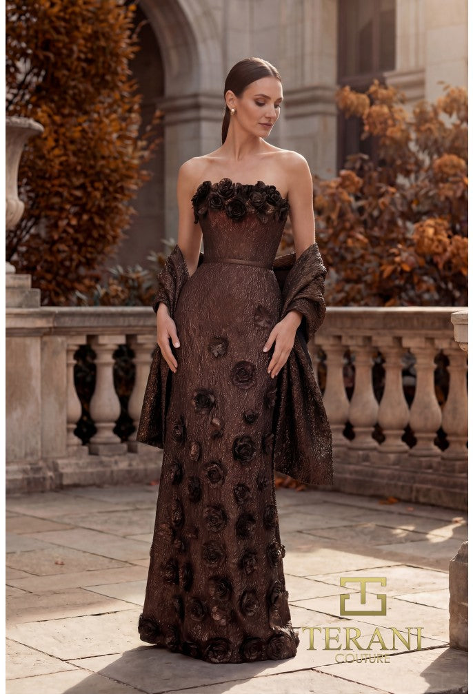 Woman in a bronze color strapless gown with floral details standing outdoors.