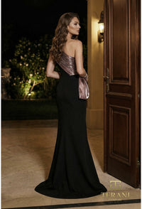 Woman in a black evening gown with metallic top standing in a doorway at night.