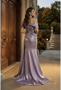 Woman in a periwinkle evening gown standing on a stone path with decorative elements.