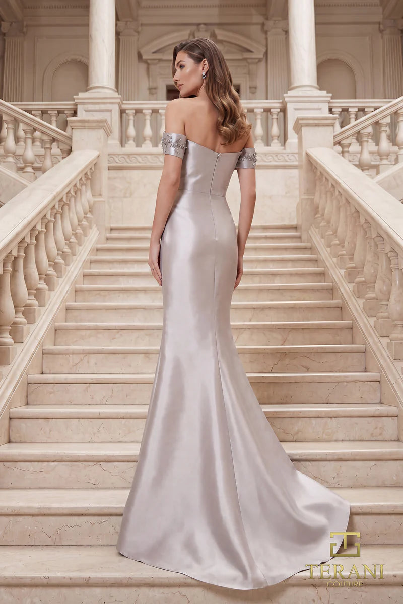 Model wearing Terani Couture 262M7254 off-the-shoulder mermaid evening gown with cap sleeves, floral appliqués, draped bodice, front slit, and sweeping train.  The model is wearing the color taupe.  Back View.