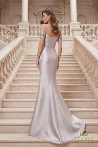 Model wearing Terani Couture 262M7254 off-the-shoulder mermaid evening gown with cap sleeves, floral appliqués, draped bodice, front slit, and sweeping train.  The model is wearing the color taupe.  Back View.