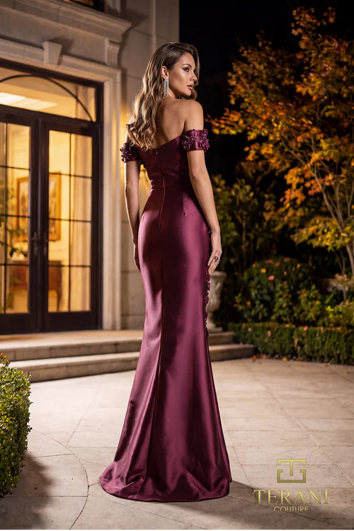 Model wearing Terani Couture 262M7254 off-the-shoulder mermaid evening gown with cap sleeves, floral appliqués, draped bodice, front slit, and sweeping train.  The model is wearing the color wine.  back View.