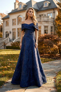 Woman in a midnight blue evening gown standing in front of a large house.