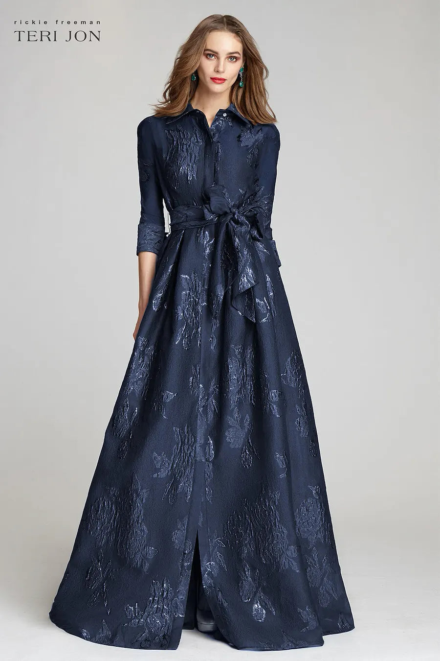 Model wearing Teri Jon 207015 floral shirt gown with a collared neckline, sash belt, three-quarter sleeves, and full A-line skirt.