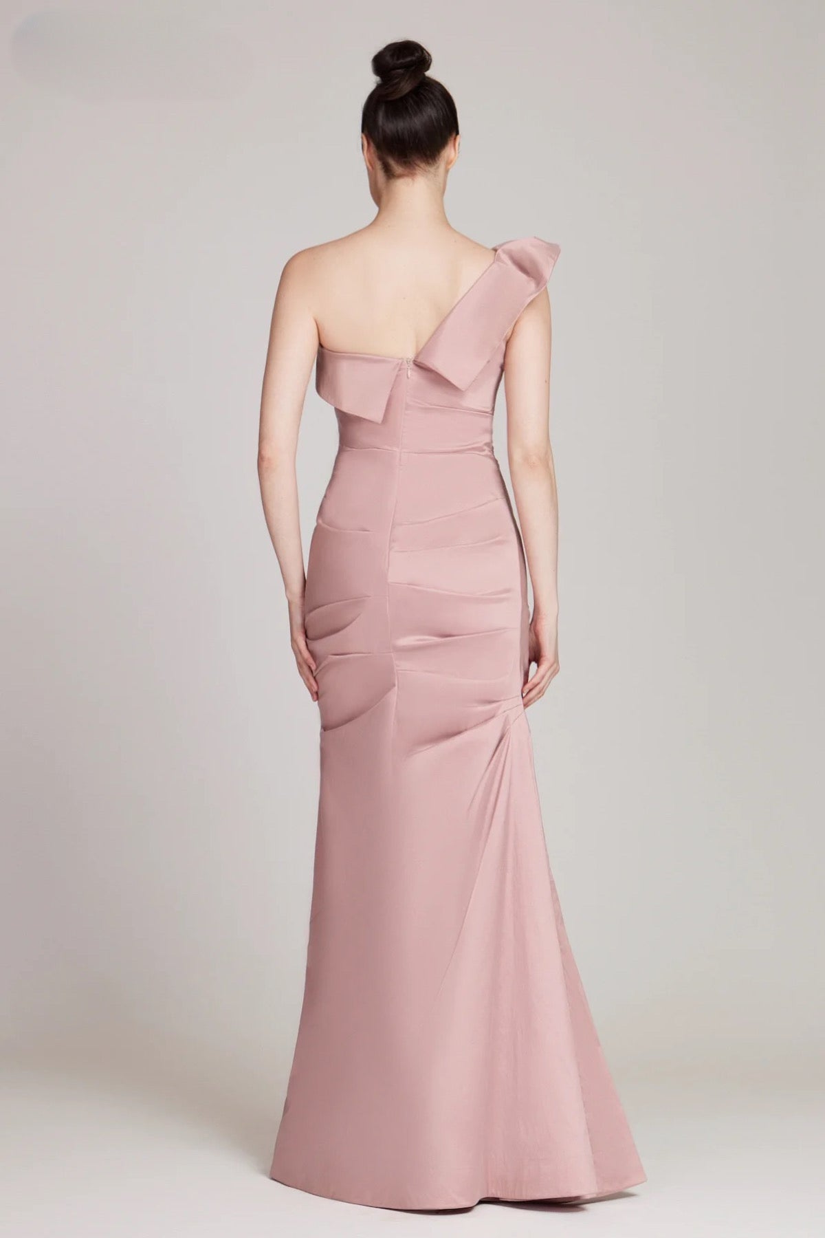 A stunning floor-length taffeta gown by Teri Jon, featuring a one-shoulder design with draped detailing, perfect for mother of the bride or groom occasions, black tie parties, and galas. Available at Madeline's Boutique in Toronto and Boca Raton.  Picture is of model wearing the dress in blush color.  Back of Dress view.