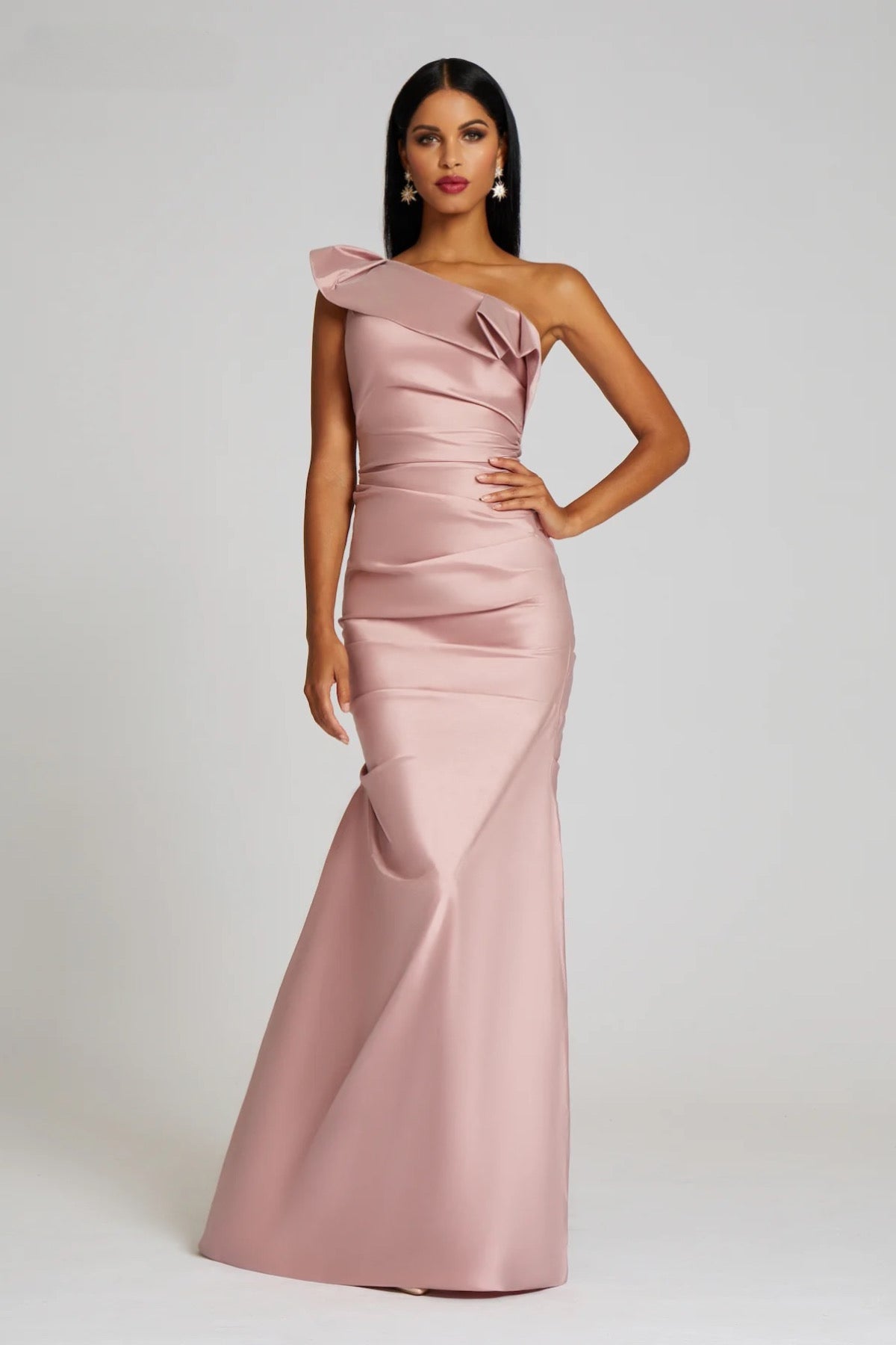 A stunning floor-length taffeta gown by Teri Jon, featuring a one-shoulder design with draped detailing, perfect for mother of the bride or groom occasions, black tie parties, and galas. Available at Madeline's Boutique in Toronto and Boca Raton.  Picture is of model wearing the dress in blush color.