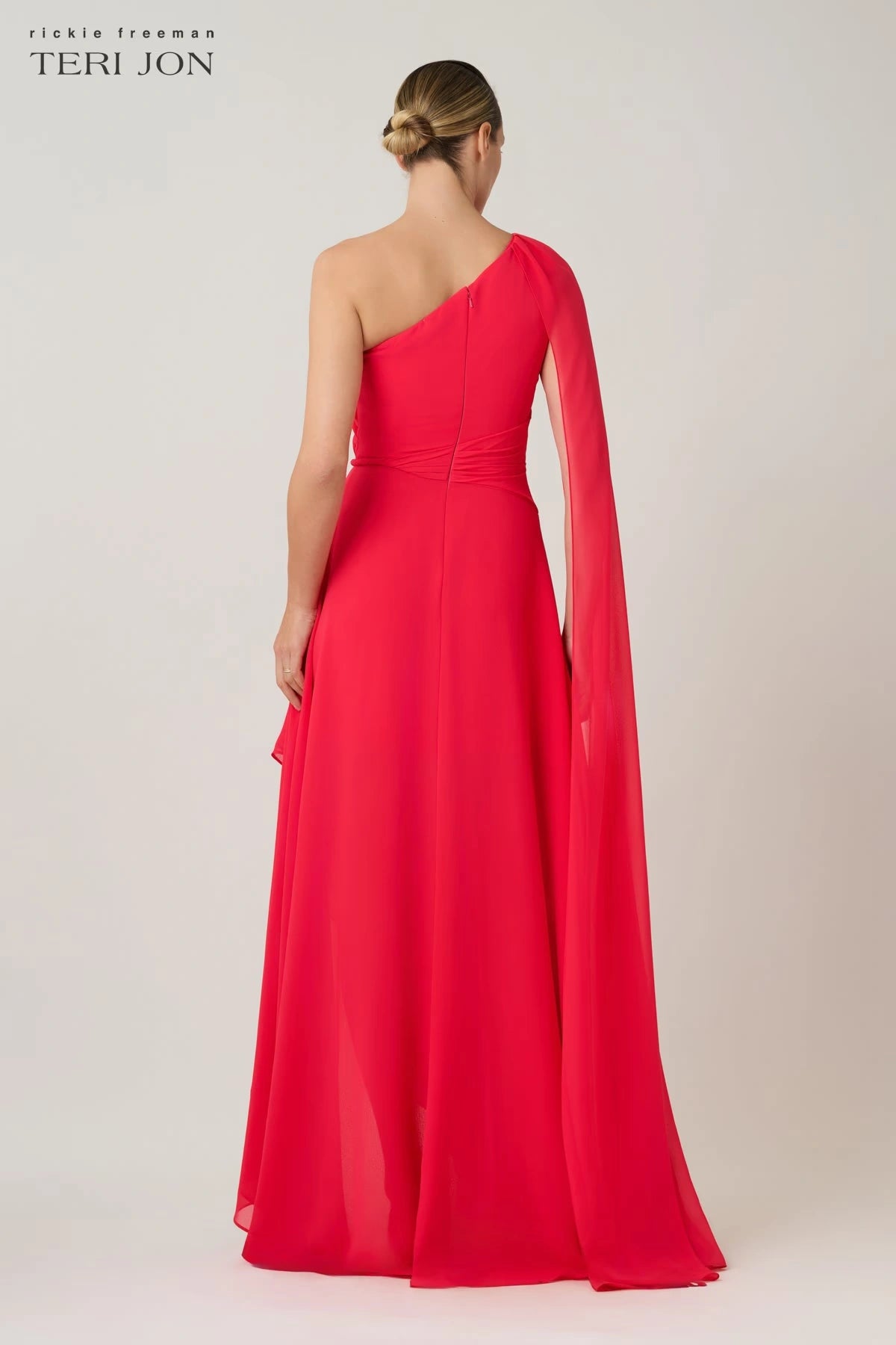 Model wearing Teri Jon 266020 one-shoulder evening gown with cape sleeve detail.