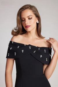 Elevate your style with Teri Jon style 237280 little black dress. Straight fit silhouette with off-the-shoulder sleeves and jeweled detailing. Perfect for cocktail parties and special events. Available at Madeline's Boutique, Toronto & Boca Raton.