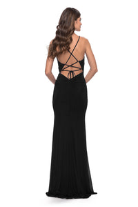 Turn heads in the stunning La Femme 31124 prom dress. This gorgeous net jersey gown features a high slit, cutouts on the waist, and spaghetti straps for a bold and sexy look. The back is adorned with an open lace-up tie back detail, making it perfect for those who love to make an entrance. The back zipper closure ensures a secure and comfortable fit. Sold by Madeline's Boutique in Toronto, Canada and Boca Raton, Florida.  Picture is of model wearing the dress in the color black.  Back view.