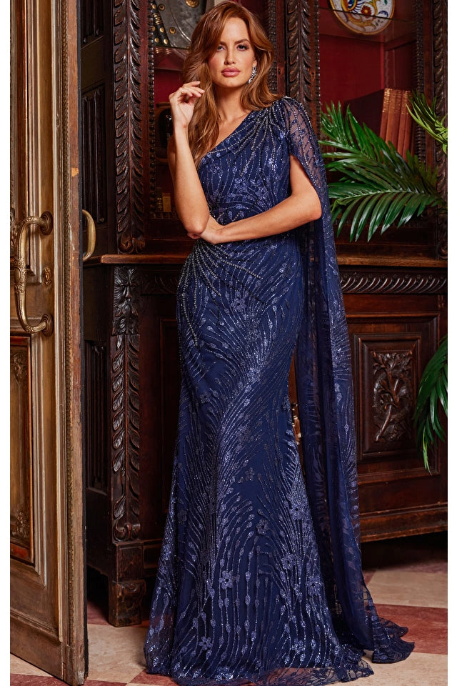 Navy Jovani Dress Style 23354 - One-Shoulder Embellished Evening Dress with Cape, made of mesh and glitter fabric, adorned with beads and stones. Perfect for evening events, black tie occasions, or mother of the bride/groom. Sold by Madeline's Boutique